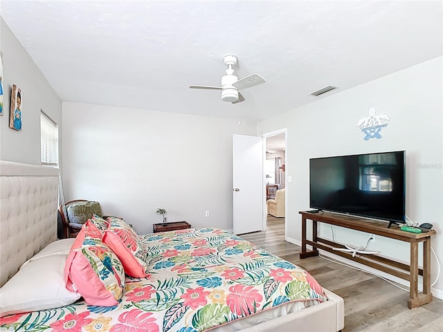 bedroom with ceiling fan, visible vents, baseboards, and wood finished floors