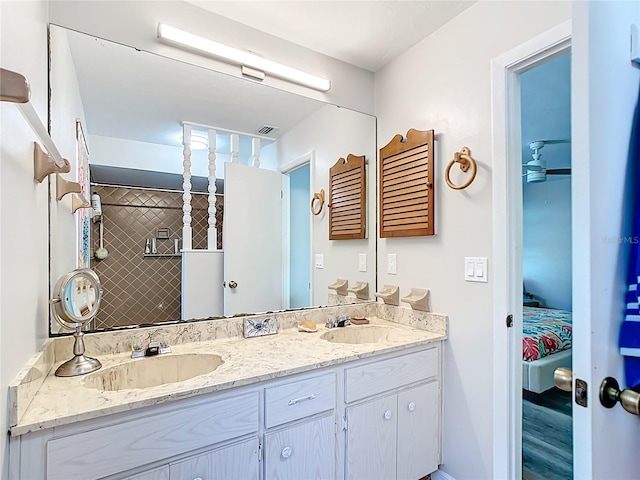 ensuite bathroom featuring double vanity, visible vents, connected bathroom, and a sink