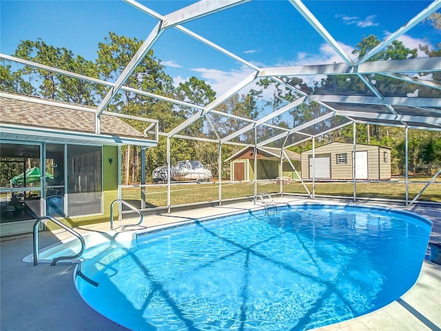 outdoor pool with an outbuilding, glass enclosure, a patio area, and a storage shed