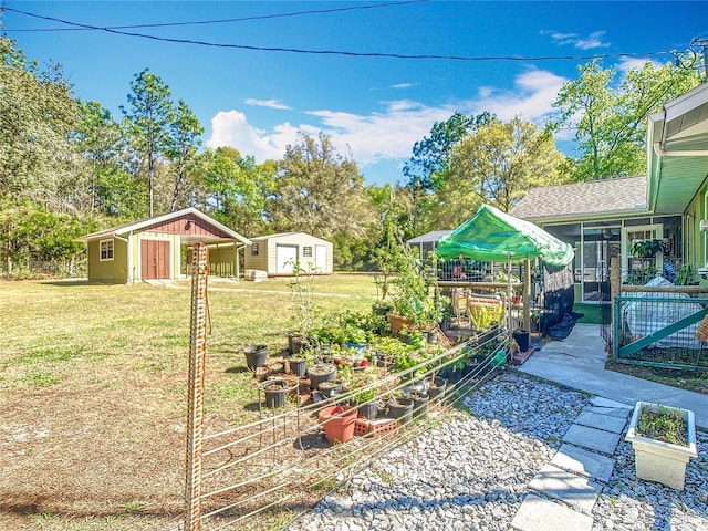 view of yard featuring an outdoor structure, a vegetable garden, and a sunroom