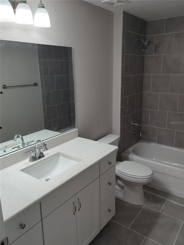 bathroom with tile patterned flooring, tub / shower combination, toilet, a textured wall, and vanity