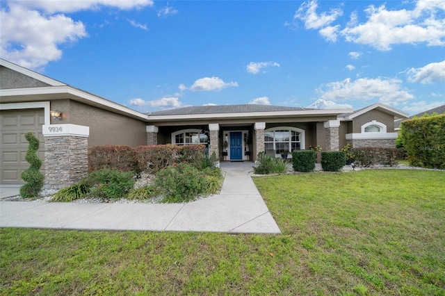 ranch-style house featuring a front yard, a garage, stone siding, and stucco siding