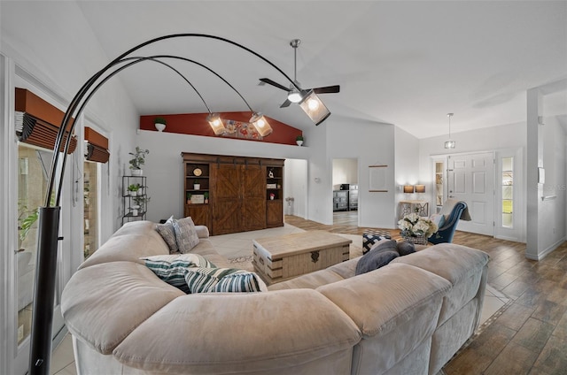 living area with baseboards, a ceiling fan, lofted ceiling, and wood finished floors