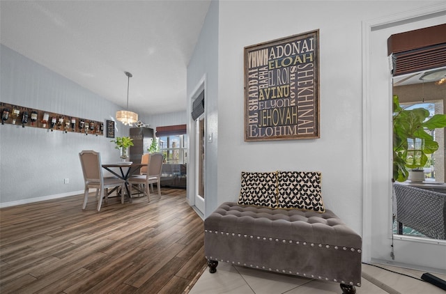 living area with vaulted ceiling, wood finished floors, baseboards, and a chandelier