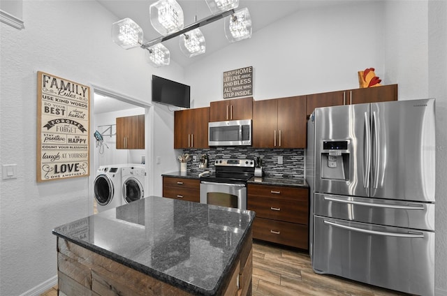 kitchen featuring backsplash, a kitchen island, wood finished floors, washer and dryer, and stainless steel appliances