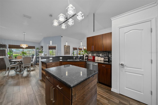 kitchen featuring dark wood-style floors, a peninsula, a sink, hanging light fixtures, and backsplash