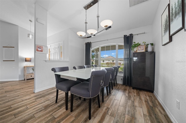 dining space with visible vents, baseboards, wood tiled floor, and a textured wall