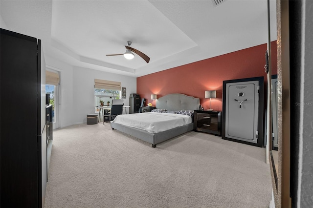 bedroom with ceiling fan, a tray ceiling, baseboards, and light carpet