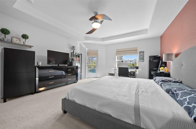 bedroom featuring a ceiling fan, a raised ceiling, access to outside, and light colored carpet