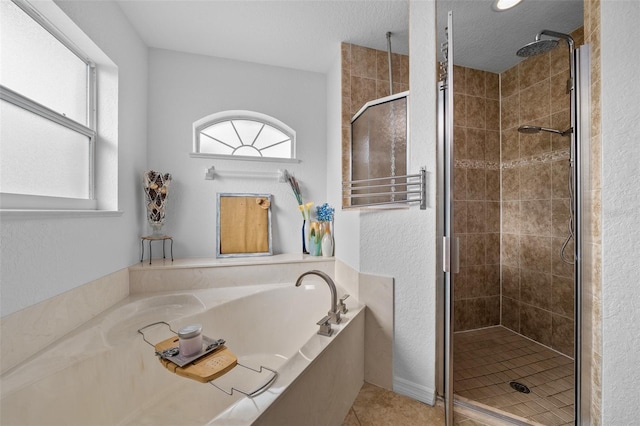 full bathroom with tile patterned flooring, a shower stall, a textured ceiling, and a garden tub