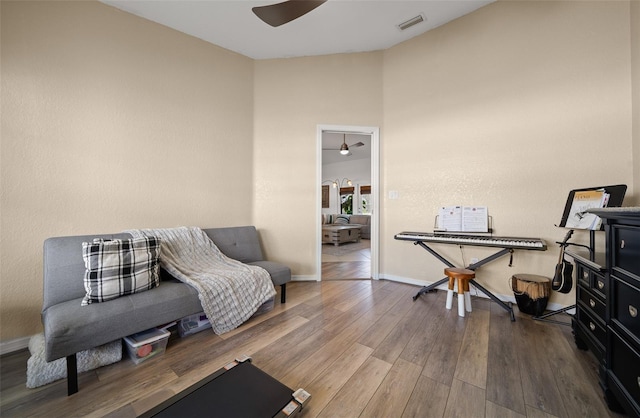 living area with ceiling fan, visible vents, baseboards, and wood finished floors