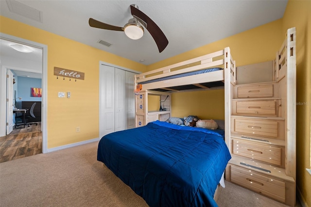 carpeted bedroom with a closet, visible vents, baseboards, and a ceiling fan