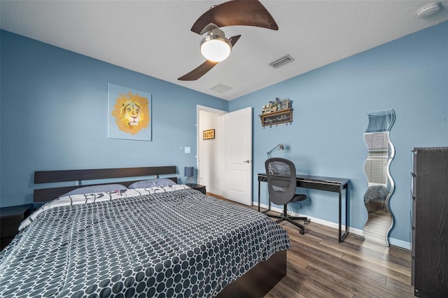 bedroom with ceiling fan, wood finished floors, visible vents, and baseboards