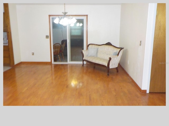 sitting room with baseboards, an inviting chandelier, and wood finished floors