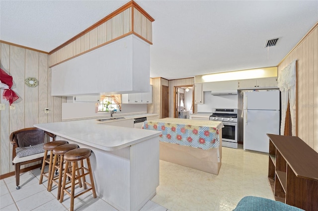 kitchen with visible vents, light countertops, a peninsula, white appliances, and a sink