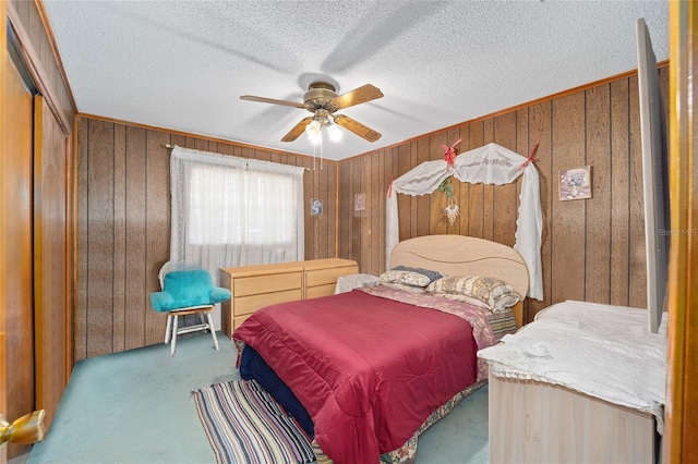 bedroom with a ceiling fan, wood walls, carpet floors, and a textured ceiling