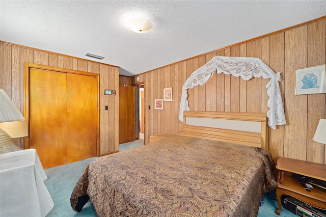 bedroom with carpet, wood walls, and a textured ceiling