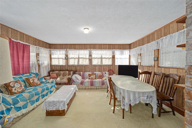 carpeted dining space with wooden walls and a textured ceiling