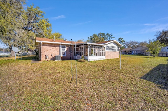 back of house featuring brick siding, cooling unit, a yard, and a sunroom