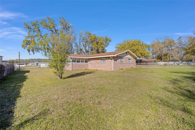 exterior space with a lawn, brick siding, and a fenced backyard