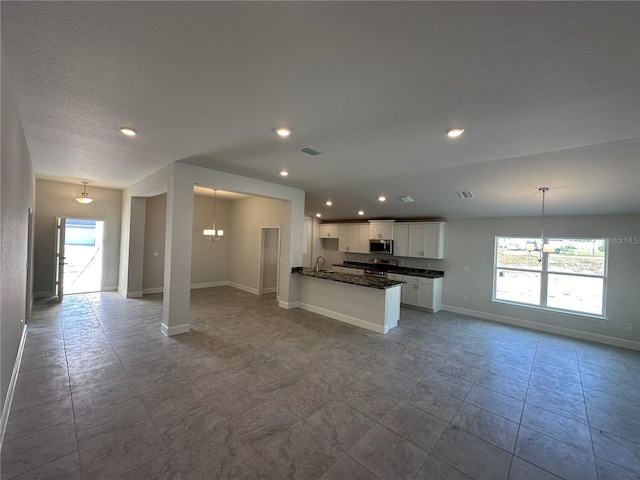 kitchen featuring white cabinets, visible vents, open floor plan, and stainless steel appliances