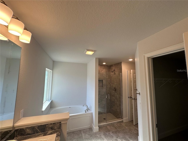 bathroom featuring a stall shower, a textured ceiling, a walk in closet, and a garden tub