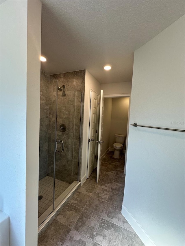 full bath featuring baseboards, toilet, a shower stall, and a textured ceiling