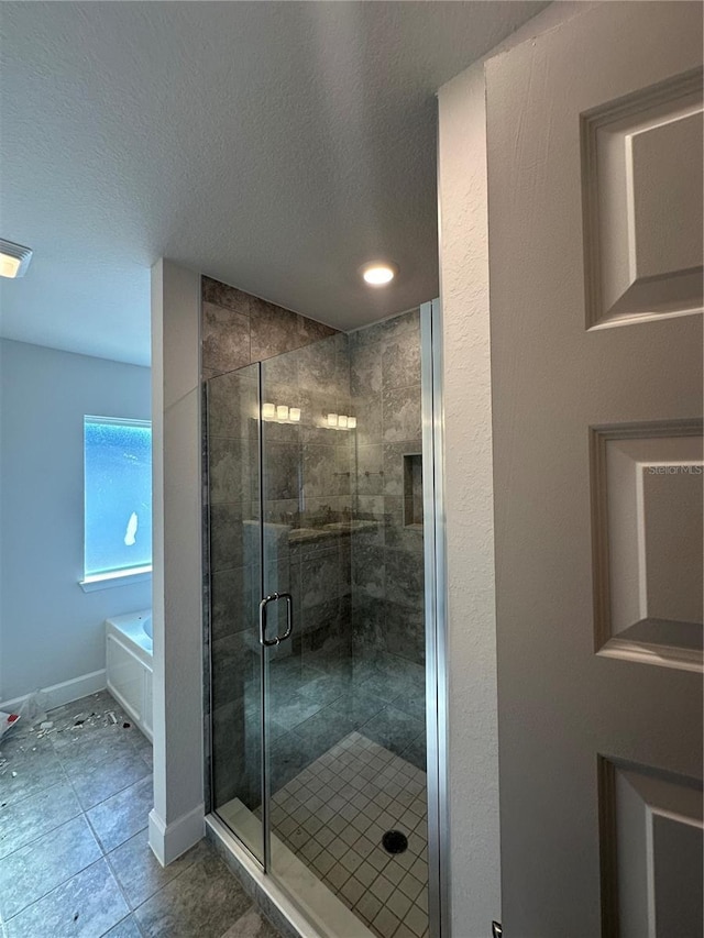 bathroom with baseboards, a garden tub, a stall shower, and a textured ceiling