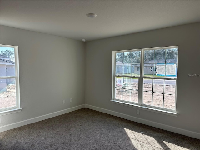 unfurnished room with baseboards and dark colored carpet