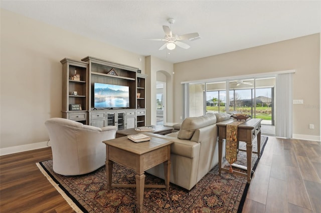 living room with ceiling fan, baseboards, arched walkways, and dark wood finished floors