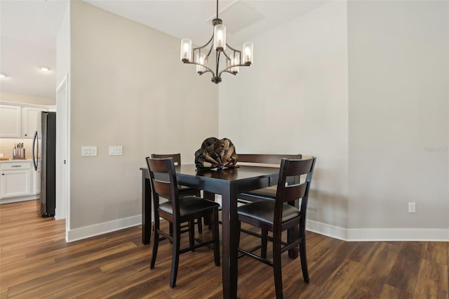 dining area featuring dark wood-style floors, a notable chandelier, and baseboards