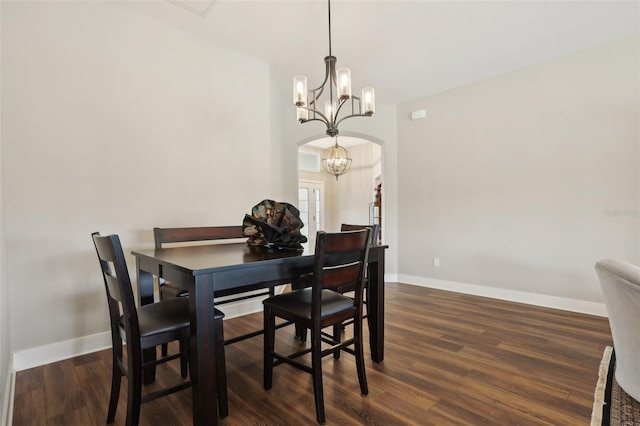 dining space featuring an inviting chandelier, dark wood-style floors, arched walkways, and baseboards