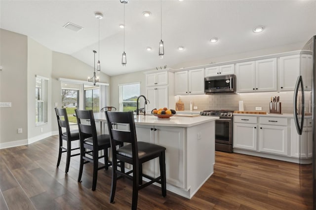 kitchen featuring stainless steel appliances, white cabinetry, backsplash, and vaulted ceiling