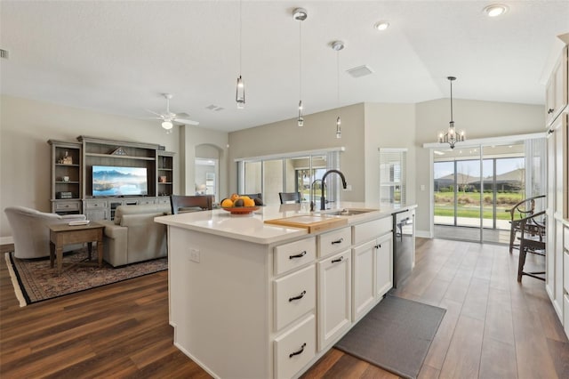 kitchen with dark wood-type flooring, an island with sink, arched walkways, and a sink