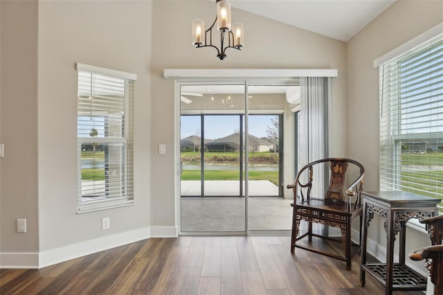 dining room featuring an inviting chandelier, vaulted ceiling, wood finished floors, and baseboards