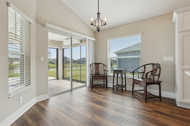 living area with baseboards, a chandelier, lofted ceiling, a wall mounted AC, and dark wood-style flooring