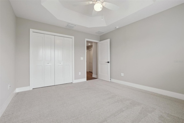 unfurnished bedroom with a raised ceiling, visible vents, baseboards, and carpet floors