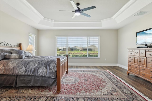 bedroom with visible vents, ornamental molding, a raised ceiling, and wood finished floors