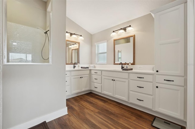 bathroom featuring baseboards, lofted ceiling, a tile shower, wood finished floors, and vanity