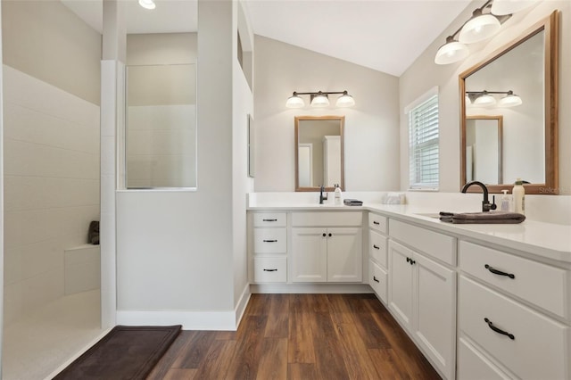 full bath with vanity, wood finished floors, baseboards, vaulted ceiling, and a walk in shower