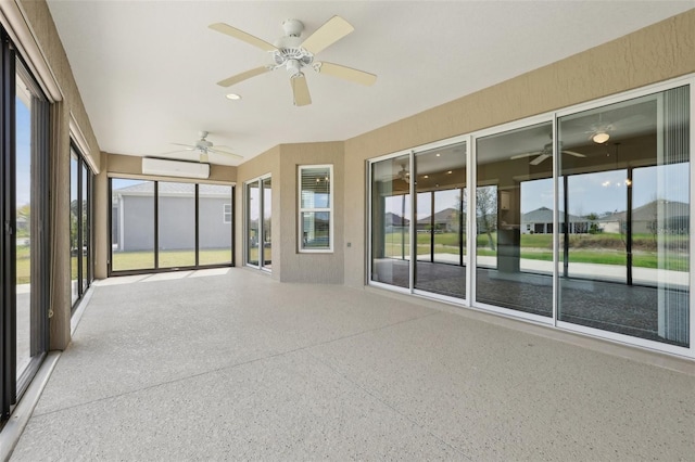 unfurnished sunroom featuring a wall unit AC and a ceiling fan