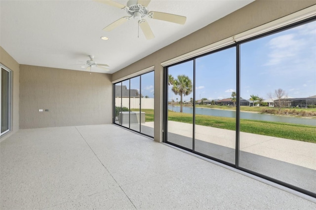 unfurnished sunroom with a ceiling fan and a water view