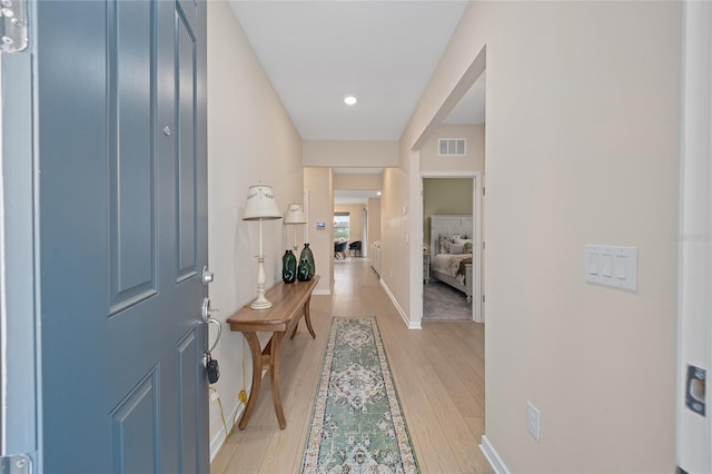 foyer entrance featuring visible vents, baseboards, and light wood-style flooring