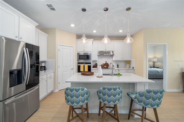 kitchen featuring visible vents, stainless steel appliances, under cabinet range hood, white cabinetry, and backsplash