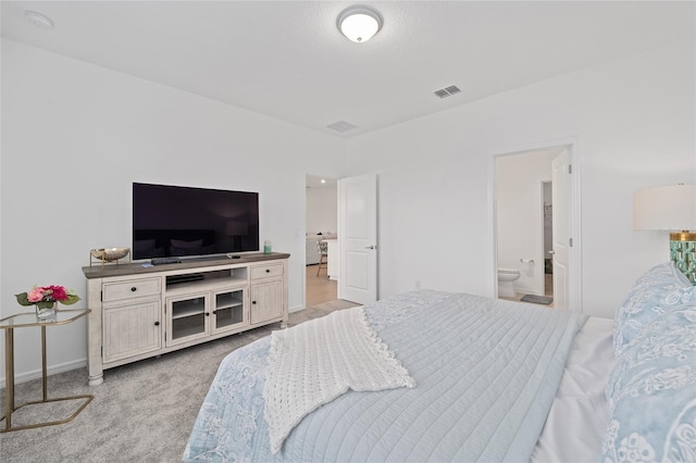 bedroom featuring visible vents, light carpet, and connected bathroom