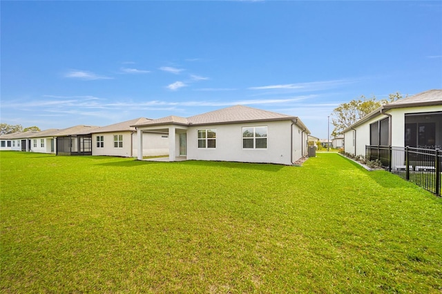 rear view of property featuring a lawn and stucco siding