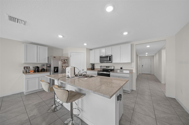 4931 SW 88th Pl, Ocala, FL 34476 - kitchen featuring visible vents, a kitchen island with sink, a sink, white cabinets, and appliances with stainless steel finishes