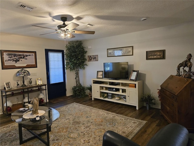 living room with visible vents, a textured ceiling, a ceiling fan, and dark wood-style flooring