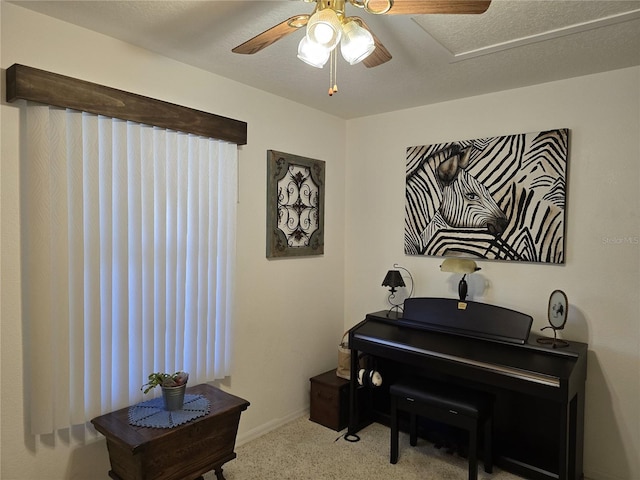 sitting room with ceiling fan, carpet, baseboards, and a textured ceiling