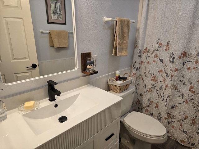 bathroom featuring a wainscoted wall, toilet, vanity, and a shower with shower curtain